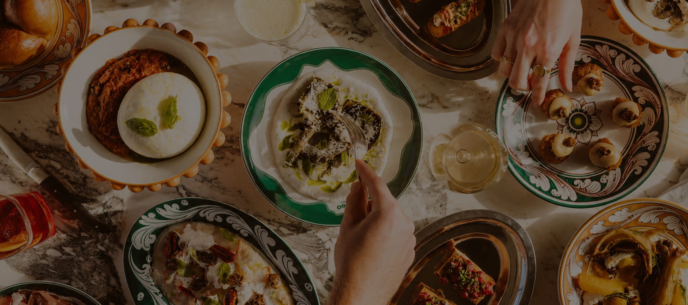 Overhead shot of a shared Bij Belle table full of antipasti, guests reaching in