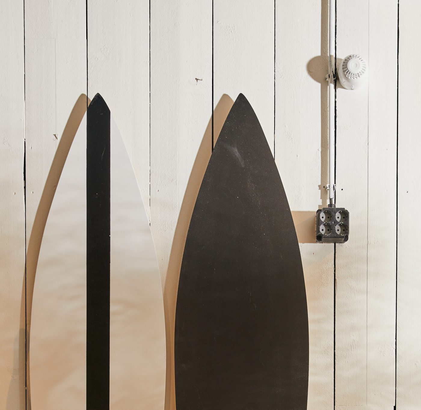 Two abstract surfboard-shaped cutouts mounted on a white panelled wall at Down Under