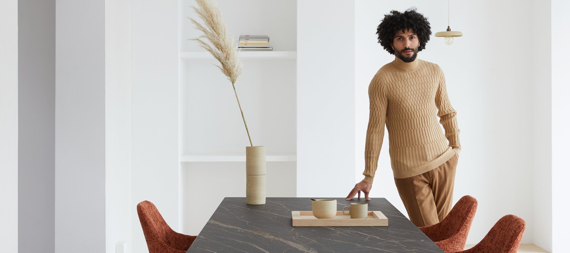 A man in a knitted sweater beside a Dyyk oak dining table