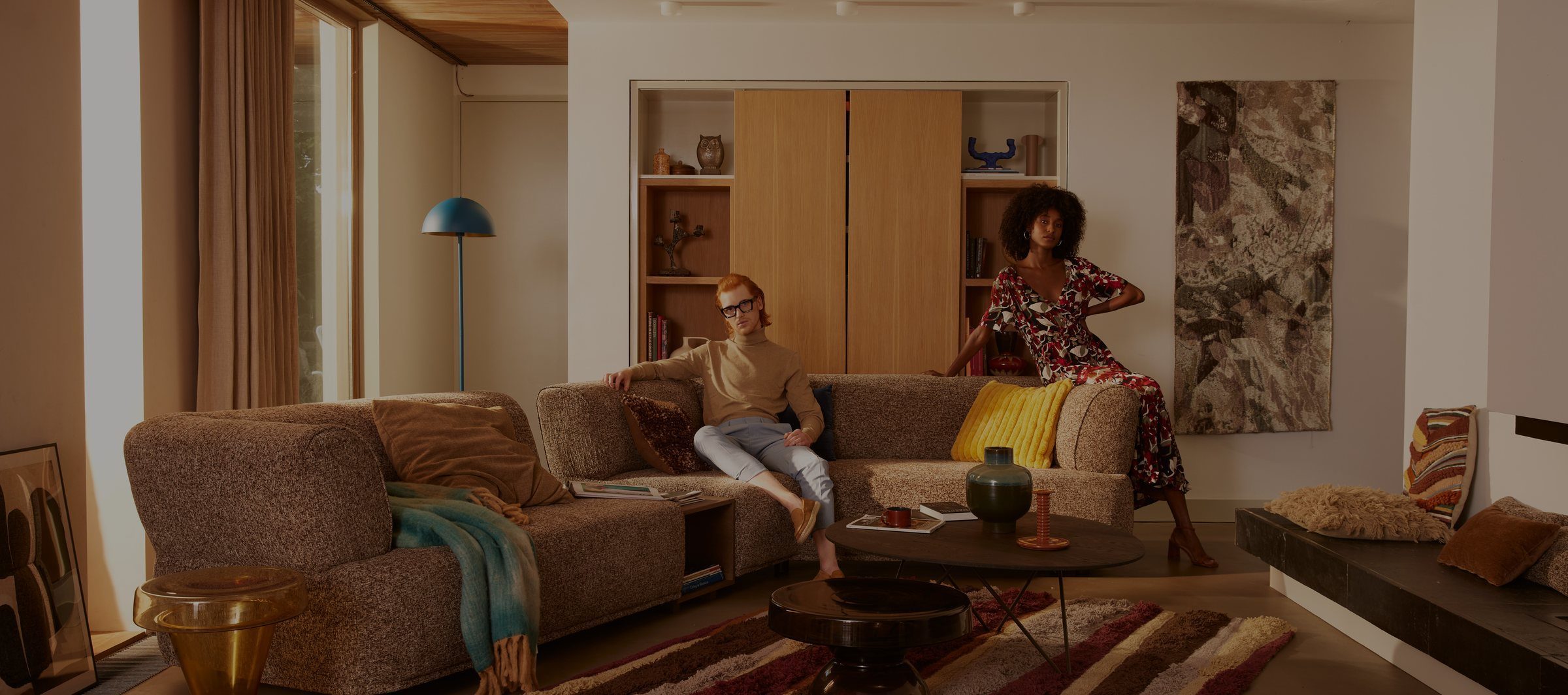 Two models relaxing in a warm, considered Dyyk living room setting