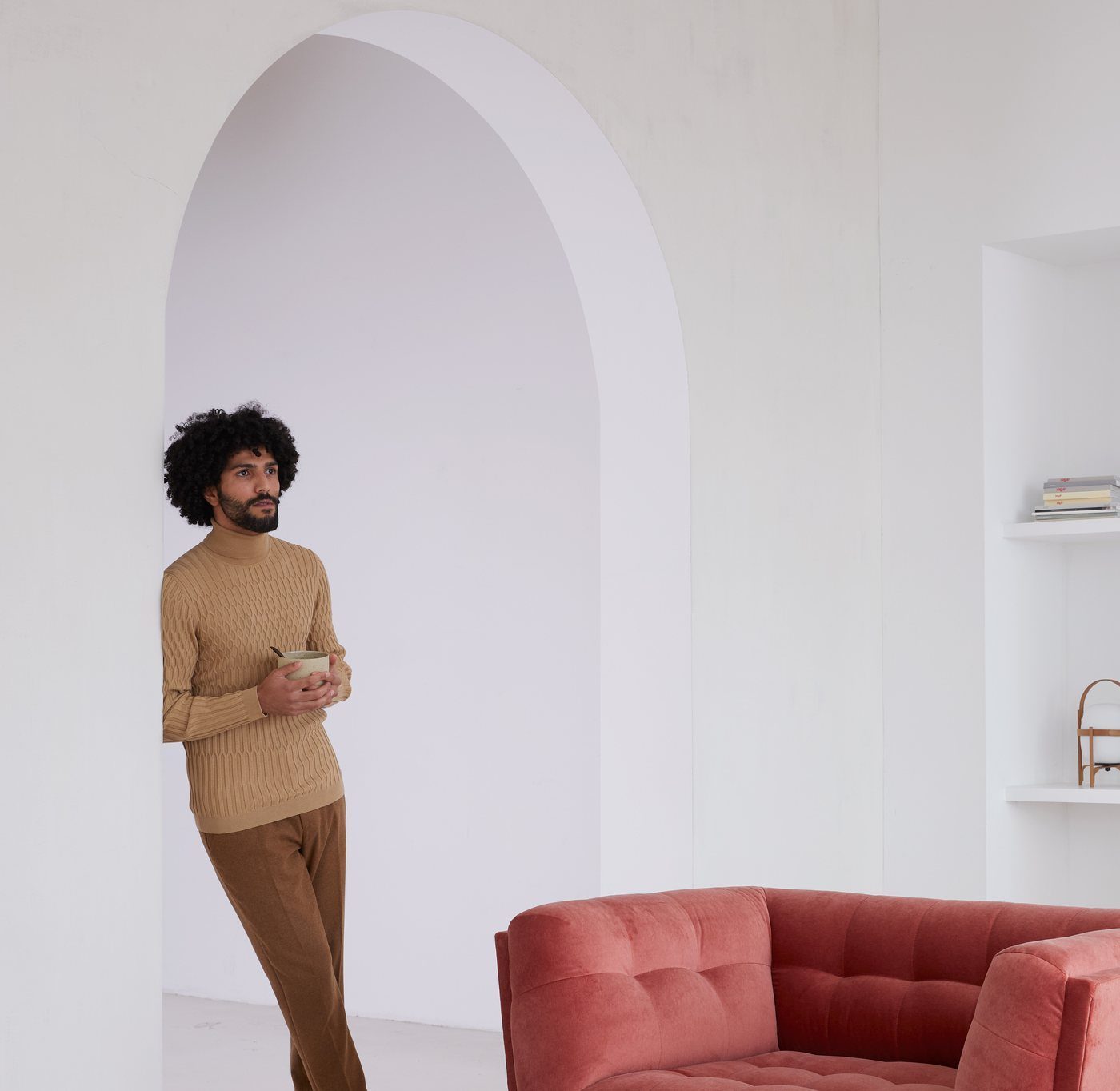 A man leaning through an archway beside a Dyyk velvet sofa