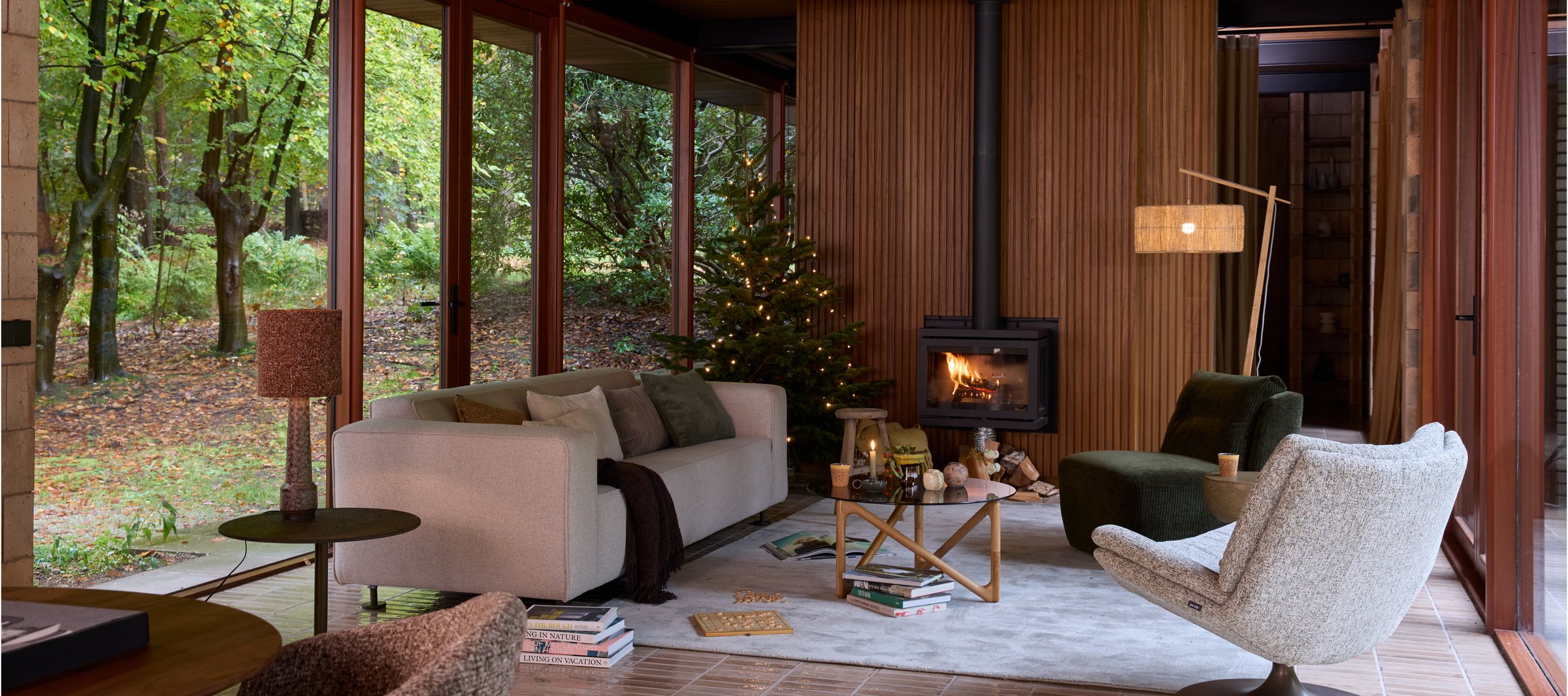 Living room in the Het Kabinet Wonen collection, wood-clad fireplace wall, sofa and a decorated Christmas tree