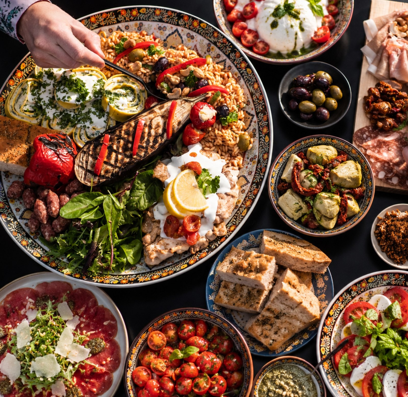 Een gastheer serveert antipasti van een overvloedig gedekte tafel