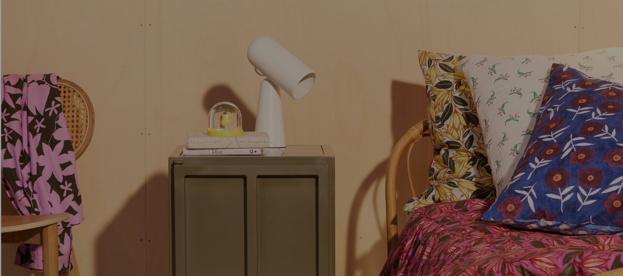 A New Routz mustard cabinet styled with books, ceramics and a plant beside a wooden staircase